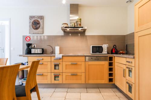 a kitchen with wooden cabinets and a microwave at Country house - La Mercerie in Continvoir