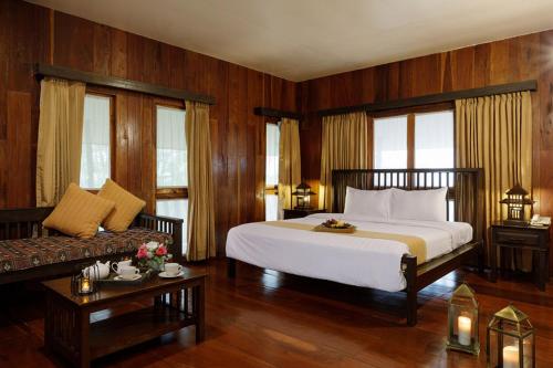 um quarto com uma grande cama branca e um sofá em Phowadol Resort And Spa em Chiang Rai