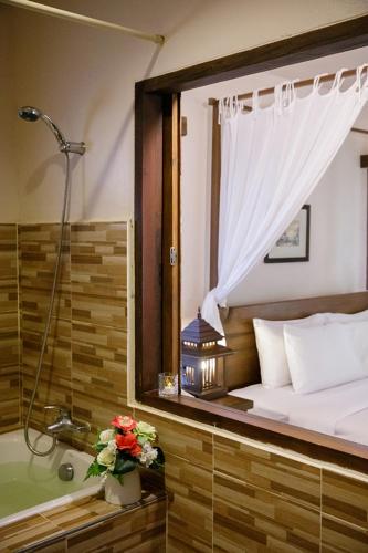 a bedroom with a tub and a bed and a shower at Phowadol Resort in Chiang Rai
