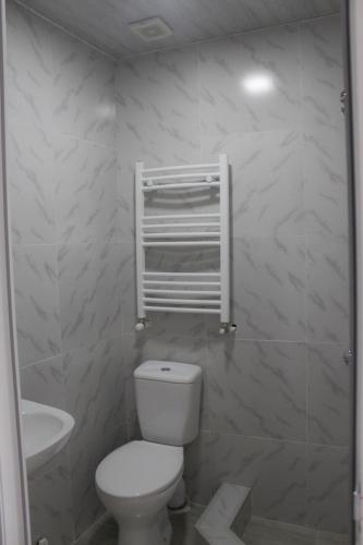 a white bathroom with a toilet and a sink at Bagration in Gori