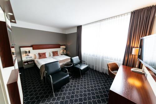 a hotel room with a bed and two chairs at Hotel Kaiserhof in Münster
