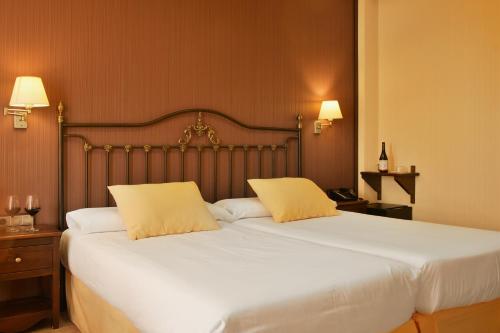 a bedroom with a large white bed with two pillows at Complejo Enoturístico Finca La Estacada in Tarancón