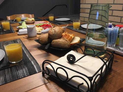 a wooden table topped with plates of food and orange juice at Lakelodge Romanshorn in Romanshorn