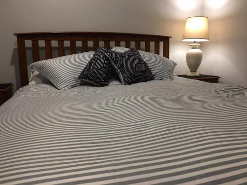 a bed with black and white sheets and a lamp at Edgehill - semi self-contained eco friendly home in Tauranga