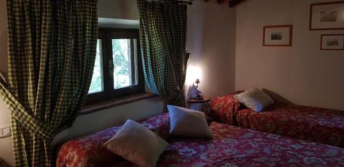 a bedroom with two beds and a window at Poggio Al Palio in San Lorenzo a Merse