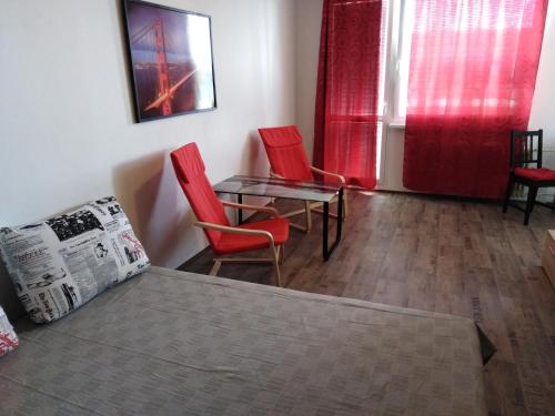モストにあるApartment Most - Brněnskáの赤い椅子、テーブル、ベッドが備わる客室です。