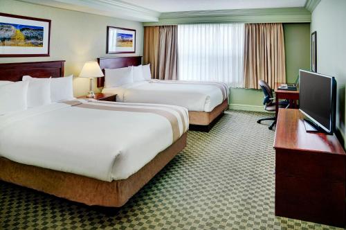 a hotel room with two beds and a desk at Chateau Nova Kingsway in Edmonton