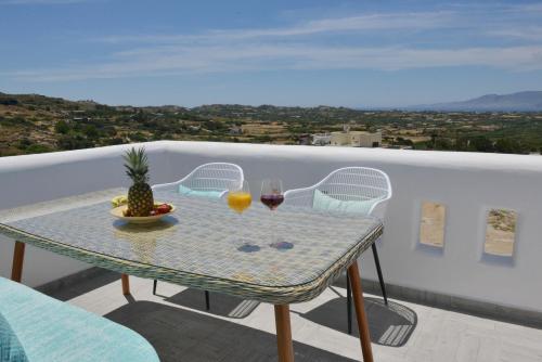 a table with two glasses of wine and a pineapple on a balcony at Villa kleio Naxian album with private pool in Glinado Naxos