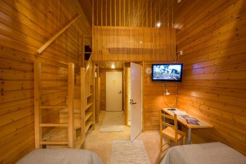 a room with wooden walls and a tv and bunk beds at Hotel Hetan Majatalo in Enontekiö