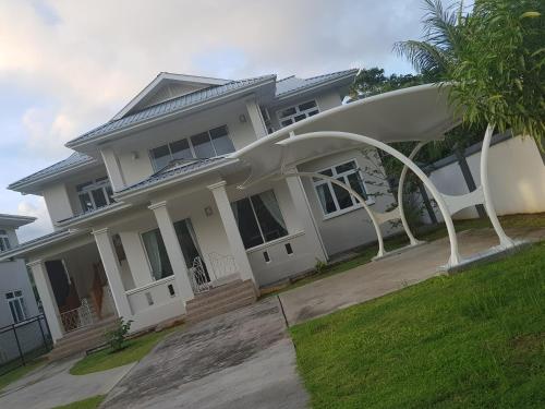 a large white house with a large arch in front of it at Maison Cattleya Selfcatering Apartment in Mahe