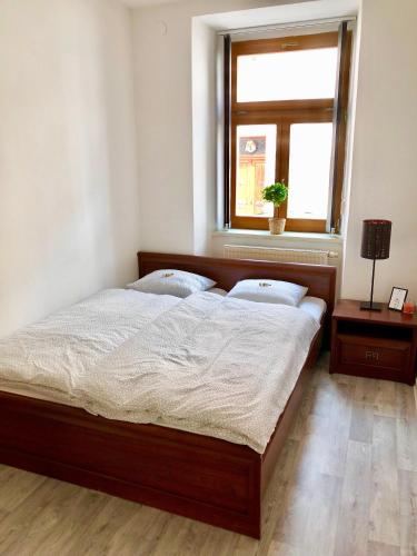 a bedroom with a large wooden bed with a window at Apartmán Pisek centrum in Písek