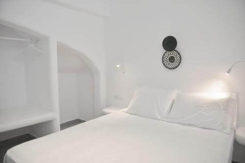 a white bed with white pillows and a clock on the wall at Villa kleio Naxian album with private pool in Glinado Naxos