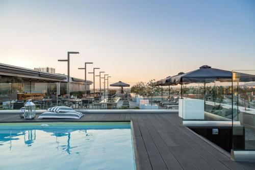 a swimming pool with tables and umbrellas on a building at Porto Palace Hotel Thessaloniki in Thessaloniki