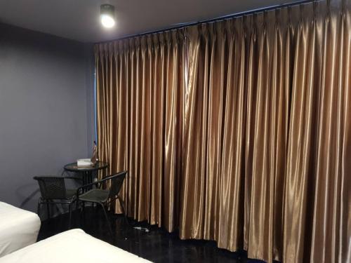 a bedroom with a curtain with a table and a chair at SleepCatsHostel in Bangkok