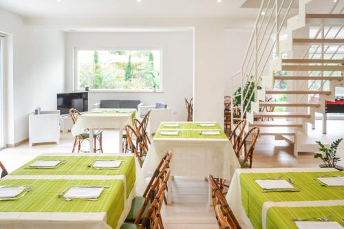 una sala da pranzo con tavoli verdi e sedie in legno di Villa Giulia a Crotone