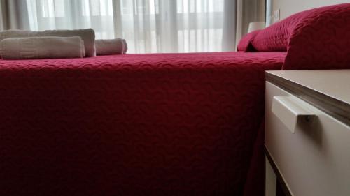 a red bed in a room with a window at Pensión Domus Gallery in Arzúa