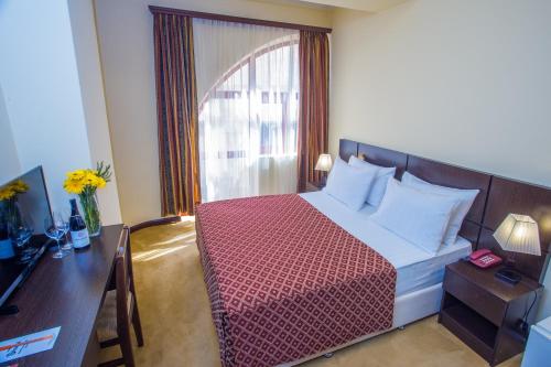 a bedroom with a bed and a desk and a window at Ani Central Inn in Yerevan