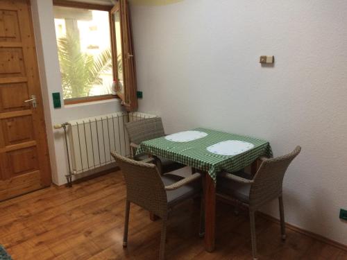 uma mesa verde e cadeiras num quarto com uma janela em Apartman Németh em Hévíz