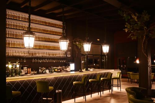 Un bar con sillas verdes y un mostrador con vasos. en Complejo Enoturístico Finca La Estacada, en Tarancón