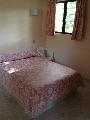 a bedroom with a bed and a chair and a window at Hotel Tecozautla in Tecozautla