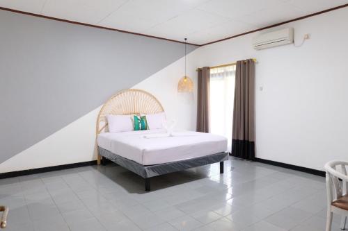 um quarto com uma cama num quarto branco em Rarem Bed & Breakfast em Bandar Lampung