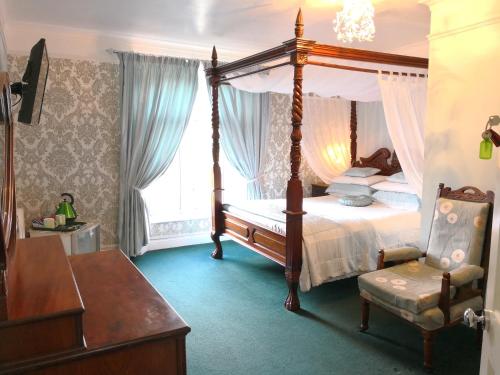 um quarto com uma cama de dossel e uma cadeira em Arches B&B em St Austell