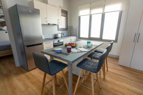 Il comprend une cuisine équipée d'une table, de chaises et d'un réfrigérateur. dans l'établissement Heraklion chic and minimalistic apartment with sea view, à Héraklion