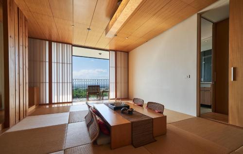 a living room with a table and a large window at Hotel Royal Chiao Hsi in Jiaoxi