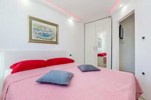 a bedroom with a pink bed with two pillows on it at Apartments Jenny in Pinezici