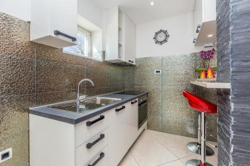 cocina con fregadero y taburete rojo en Apartments Jenny, en Pinezici