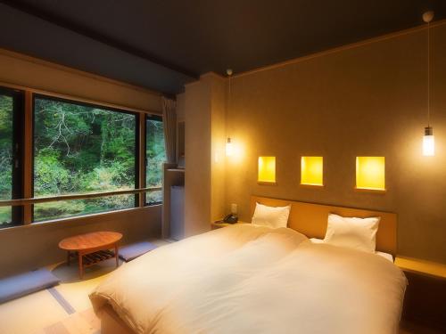 会津若松市にある庄助の宿 瀧の湯のベッドルーム(大きな白いベッド1台、窓付)