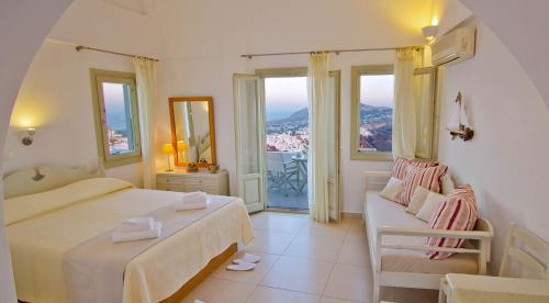 a bedroom with two beds and a couch and windows at Irida - Santorini in Imerovigli