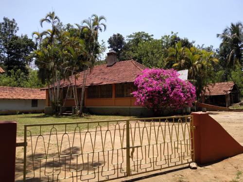 a house with a fence and pink flowers at Woodside Homestay Wayanad in Batheri
