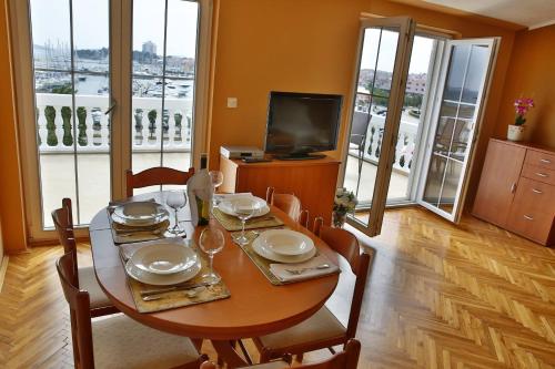 a dining room with a table with chairs and a television at Apartment and Rooms Villa Kolonada in Vodice