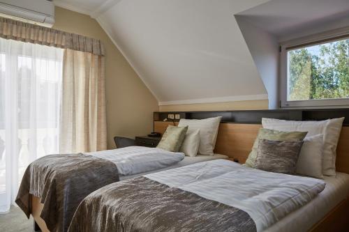 two beds in a bedroom with a window at Gold House Pension in Balatonfüred