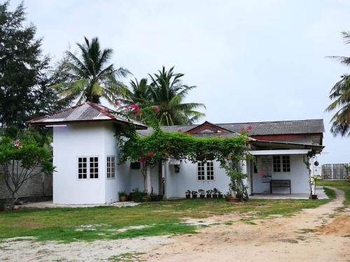 a white house with palm trees in the background at ALA Beach Lodge - Markisa Homestay in Bachok