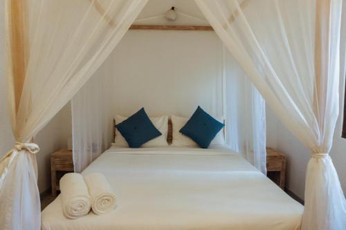 a bedroom with a white bed with blue pillows at Handun Villas in Talalla