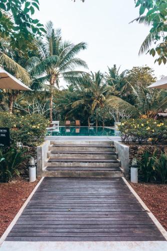 a wooden walkway leading to a resort with palm trees at Handun Villas in Talalla