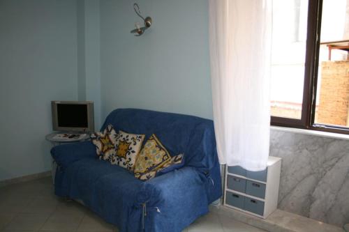 niebieska kanapa z dwoma poduszkami siedzącymi w pokoju w obiekcie Delby's house w mieście Neapol