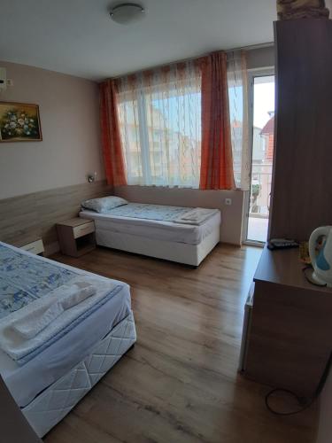 a bedroom with two beds and a large window at Guest House Diamandievi in Nesebar
