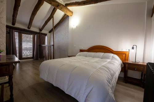 a bedroom with a large white bed and a desk at Casa Rural Pradas in Montanejos