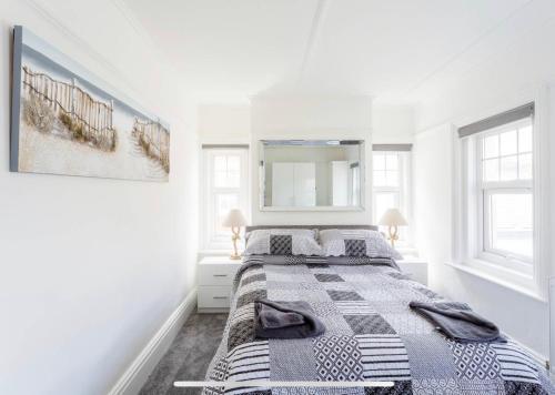a white bedroom with a bed and a mirror at Ammonite Luxury beachfront apartment in Lyme Regis