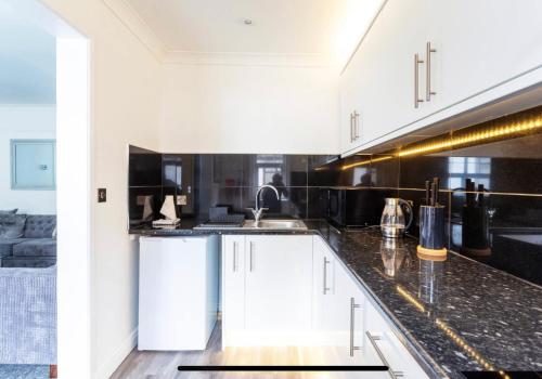 a kitchen with white cabinets and a black counter top at Ammonite Luxury beachfront apartment in Lyme Regis