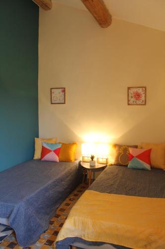 a bedroom with two beds and a table with a lamp at la verdale in Séguret