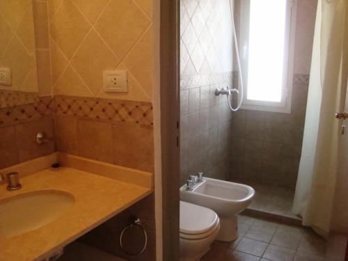 a bathroom with a toilet and a sink and a shower at Cabañas El Refugio de Juan in Mina Clavero