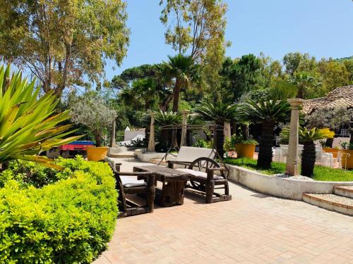 a patio with tables and benches in a park at Residenza Villa Spagnola in Parghelia