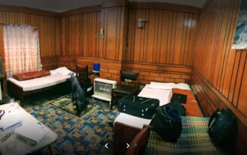 Habitación con 3 camas, escritorio y TV. en Lourdes Hotel, en Quetta