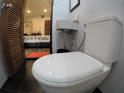 a bathroom with a white toilet in a room at The Ghee House in Chiang Mai