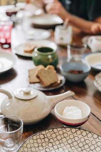 een houten tafel met borden met eten en een theepot bij La Maison d'Ambronay in Ambronay