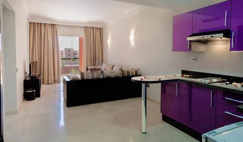 a kitchen with purple cabinets and a living room at Palm Appart Hôtel Marrakech in Marrakech